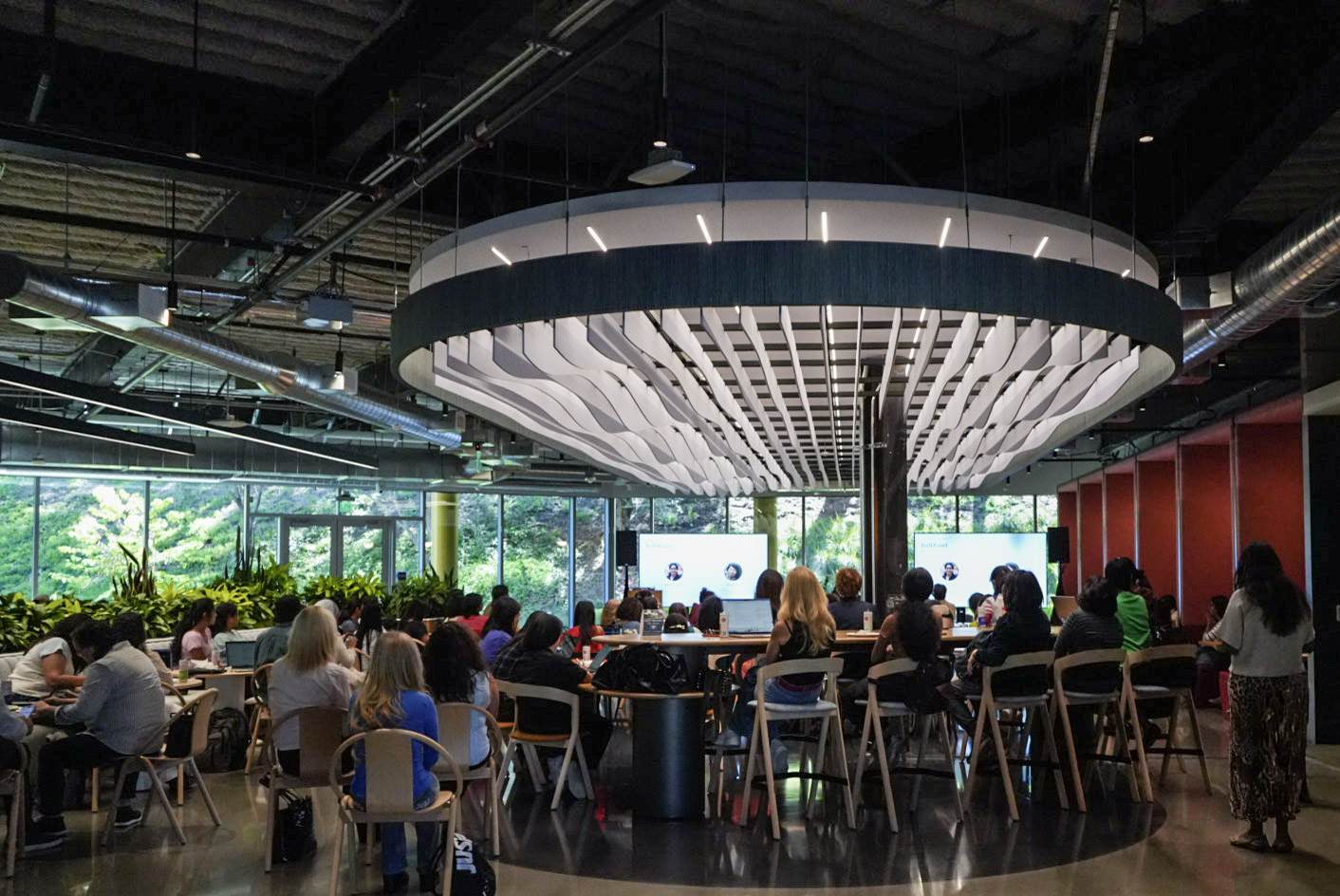 Wide view of the Women in AI gathering beneath a sculptural ceiling installation in Palo Alto
